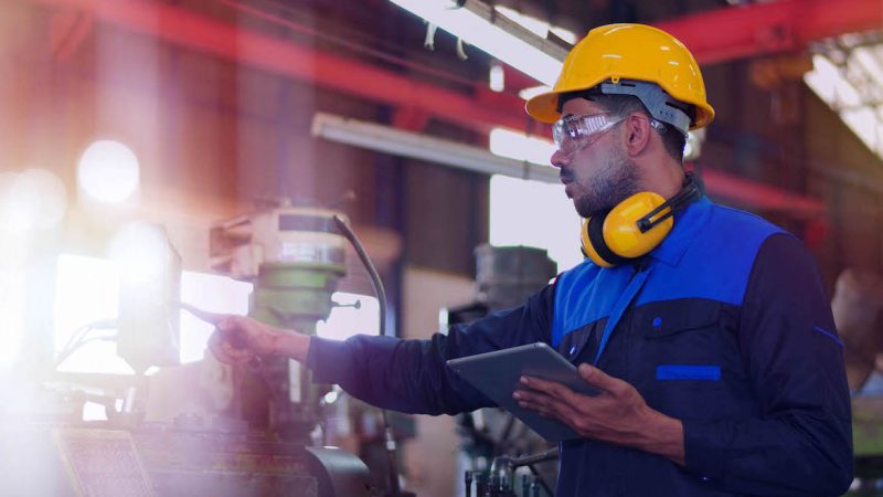 Professional maintenance engineer, technician worker, repairman wear uniform, safety hard hat using tablet computer checking control machine in factory. Manufacturing heavy machine Industry concept.