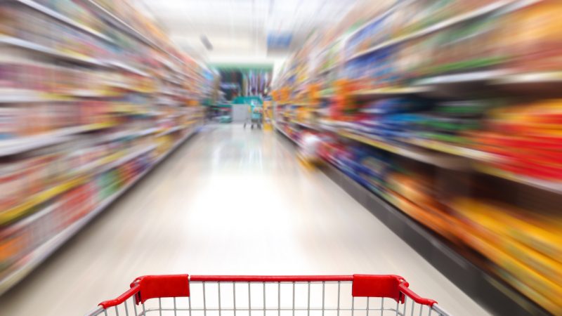 supermarket shelves aisle blurred background with shopping cart in motion